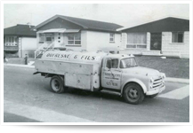 Vintage milk delivery truck in residential area.