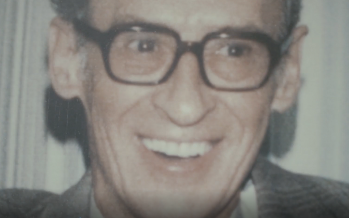 Smiling man wearing glasses and suit.