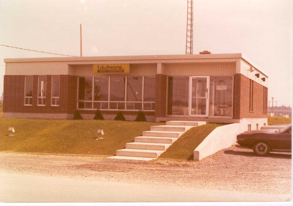 Vintage Dufresne building with glass entrance and steps.