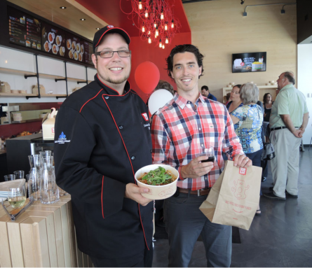Chef and customer in restaurant posing with food.