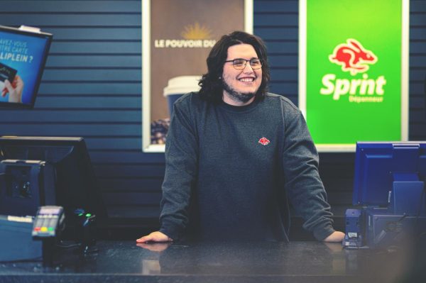 Smiling cashier at Sprint convenience store counter.