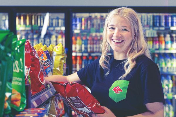 Smiling woman shopping for chips in grocery store.