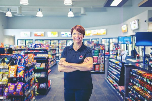 Convenience store employee smiling at camera.